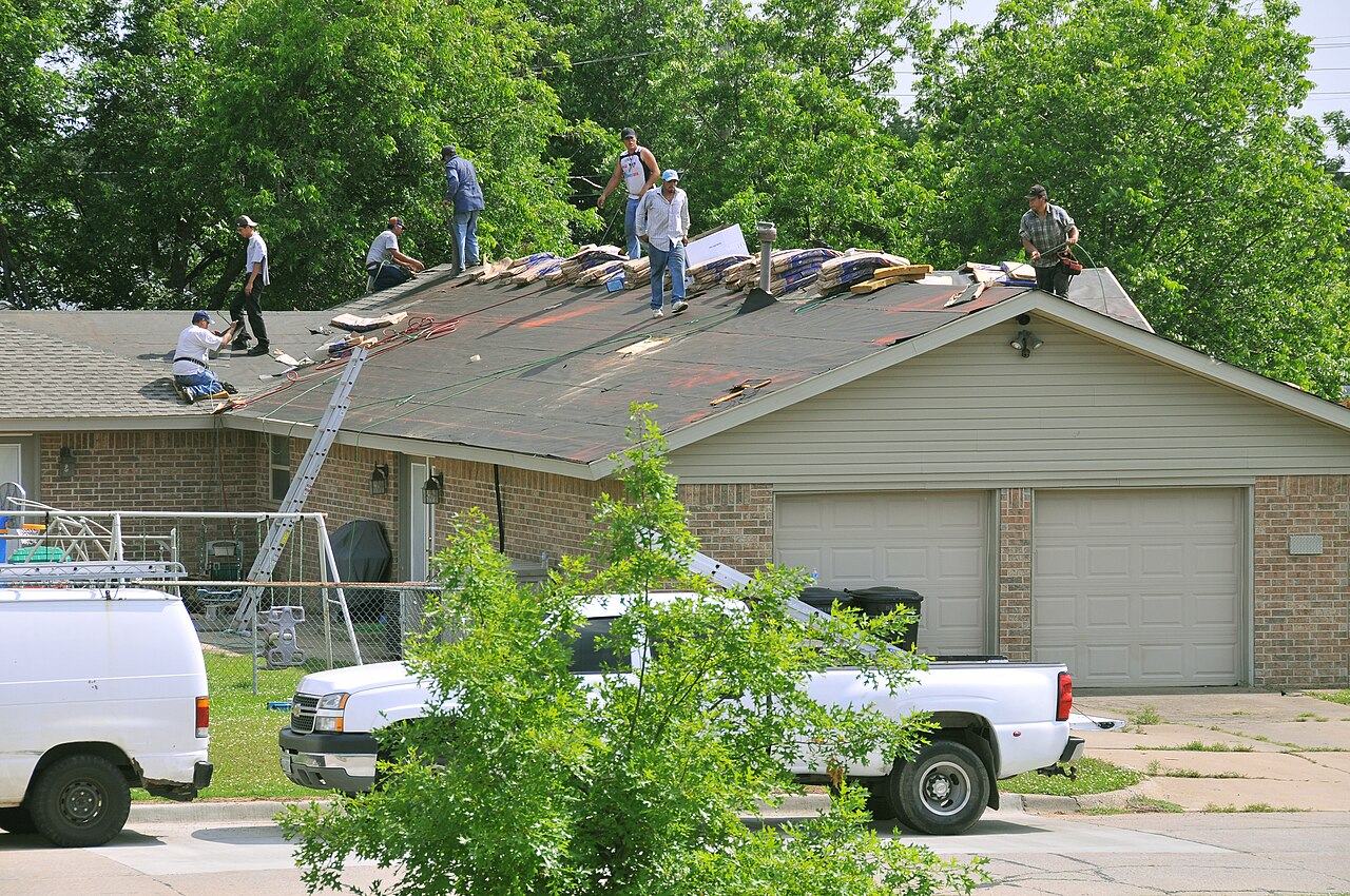 Crew tearing shingles off a house roof